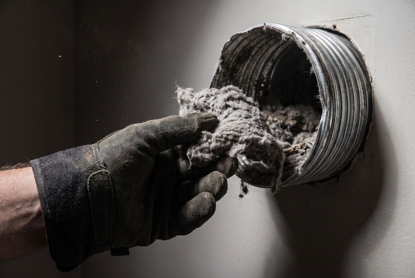 Technician removing a large clump of lint from a home dryer vent
